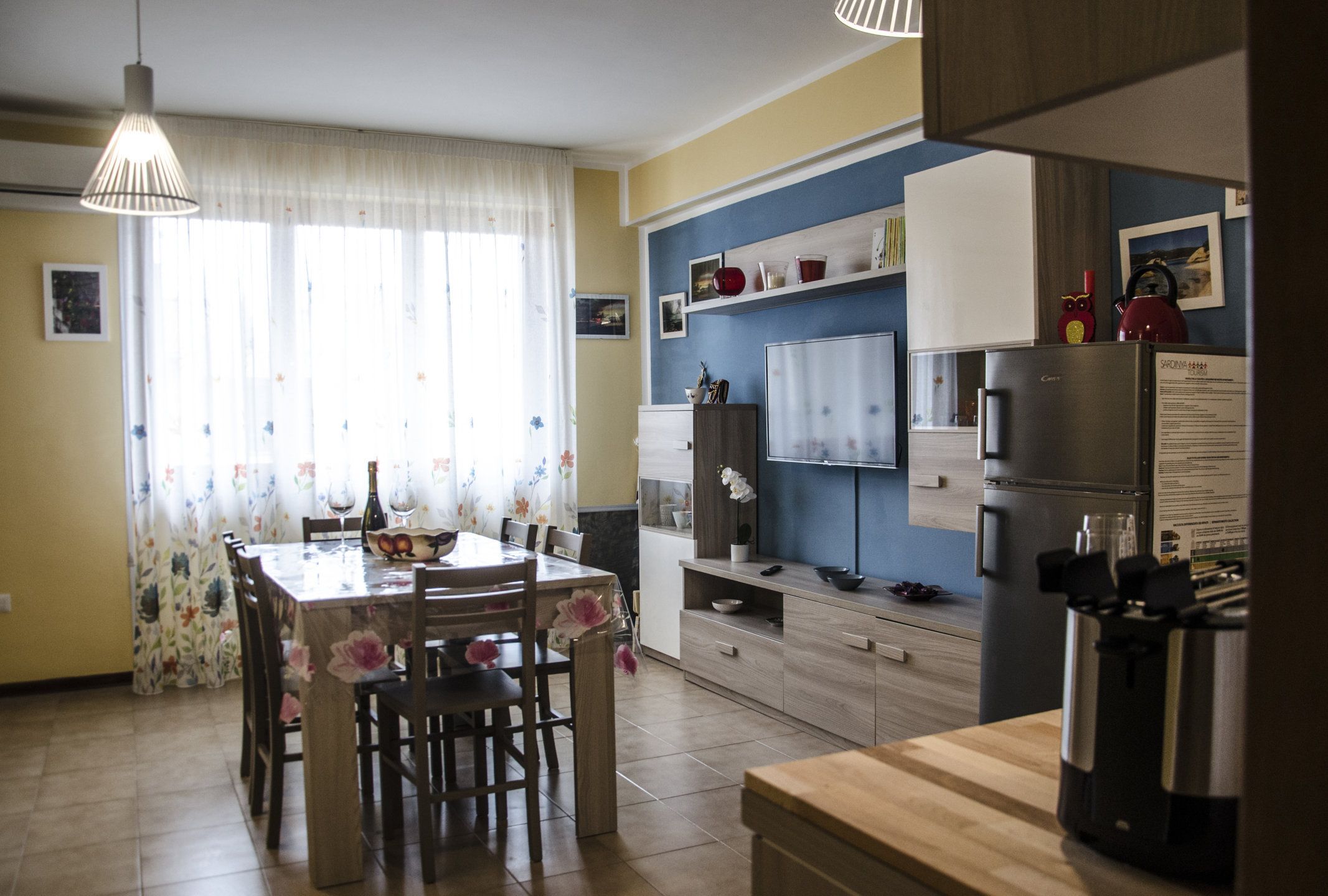 A modern kitchen with a dining table, chairs, and a refrigerator.