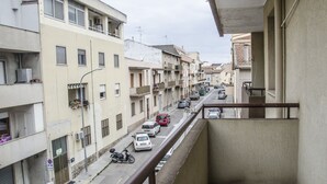 A residential street with multi-story buildings, parked cars, and a pedestrian walkway. - Casa Barracuda (Alghero)