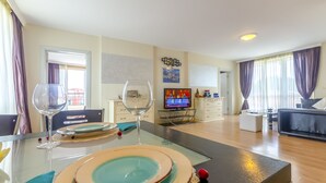 A modern living room with a dining area, a TV, and a balcony view. - Two Bedroom Apartment, Terrace in Aphrodite Palace (Sunny Beach)