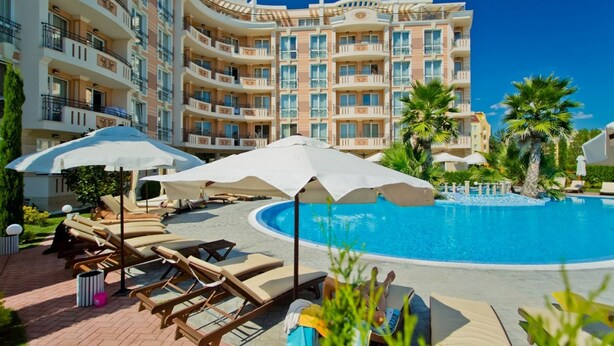 A resort with a swimming pool, sun loungers, umbrellas, and a multi-story building with balconies. - Two Bedroom Apartment, Terrace in Aphrodite Palace (Sunny Beach)