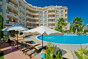 A resort with a swimming pool, sun loungers, umbrellas, and a multi-story building with balconies. - Two Bedroom Apartment, Terrace in Aphrodite Palace (Sunny Beach)