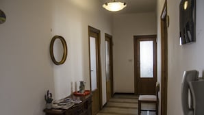 A hallway with a wooden chair, a small table with a potted plant, and a wall-mounted telephone. - Casa Tonno (Alghero)
