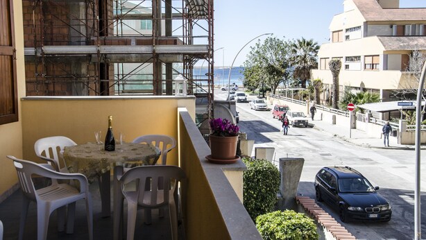 A balcony with a table, chairs, and a potted plant. - Casa Tonno (Alghero)