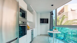 A modern kitchen with stainless steel appliances, a dining area with a round table and chairs, and a large window with a view of buildings and palm trees. - Edison Building 201 By CanariasGetaway (Las Palmas de Gran Canaria)