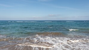 A beach with waves and a clear sky.