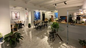 A modern interior with a dining area, a bar, and a kitchen visible in the background. - The Boutique Residence Hotel Penang (George Town)