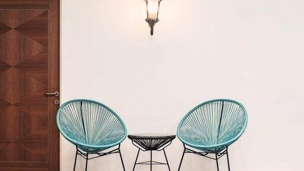 A room with a wooden door, two teal chairs, a small table, and a wall-mounted light fixture. - The Boutique Residence Hotel Penang (George Town)