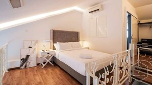 A bedroom with a bed, bedside tables, a headboard, artwork, and a railing. - The Boutique Residence Hotel Penang (George Town)
