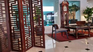 A room with a traditional wooden partition, a grandfather clock, a dining table with chairs, and a view of a swimming pool through the glass doors. - The Boutique Residence Hotel Penang (George Town)