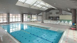 An indoor swimming pool with clear lanes, a roofed ceiling, and large windows.