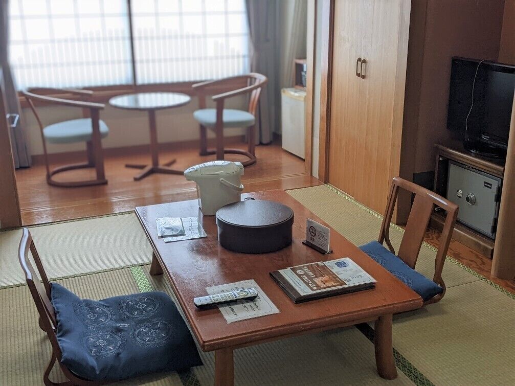 Een kamer met een houten tafel, stoelen, een televisie en een kast.