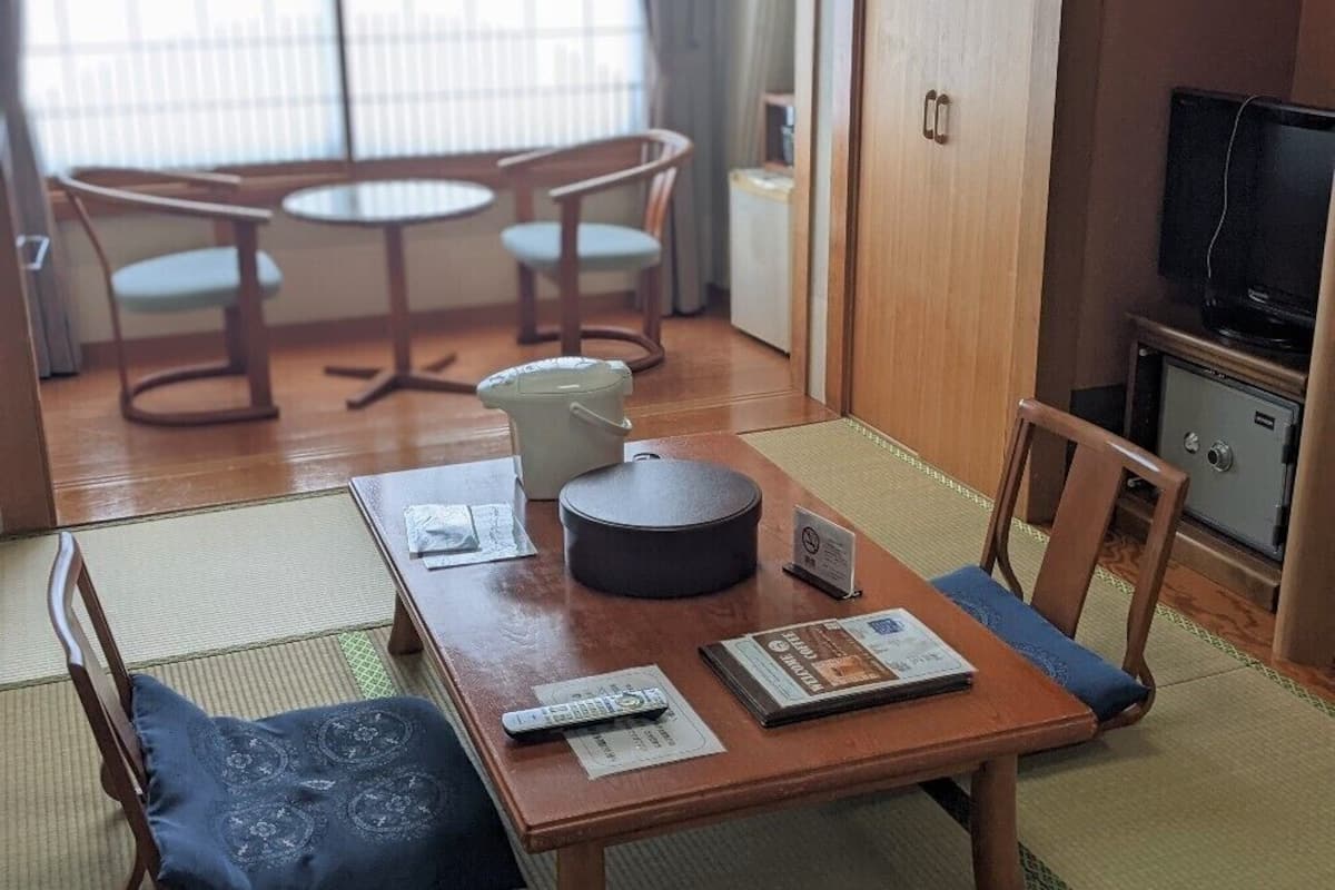 Une pièce comprenant une table en bois, des chaises, un téléviseur et un meuble.