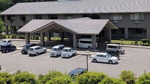 A hotel with a covered parking area, multiple vehicles, and a building with a flat roof.