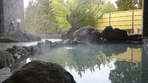 A hot spring area with rocks, a stone wall, and trees in the background. - Akita Kenkozoshin Koryu Center Yufore (Akita)