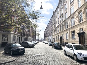 A cobblestone street lined with parked cars and historic buildings.