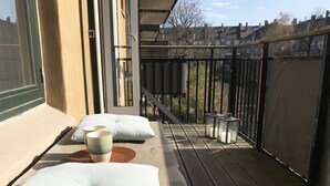 A balcony with a view of residential buildings, a cushioned seating area, and a railing. - 2 bedroom apartment Vesterbro 1372-1 (Copenhagen)