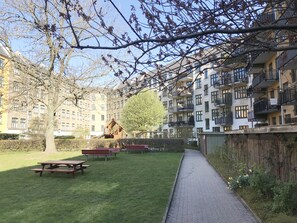 Une cour avec des tables de pique-nique, une aire de jeux et, au fond, des immeubles d’habitation.
