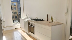 A modern kitchen with a built-in oven, dishwasher, and a large countertop. - 2 bedroom apartment Vesterbro 1372-1 (Copenhagen)