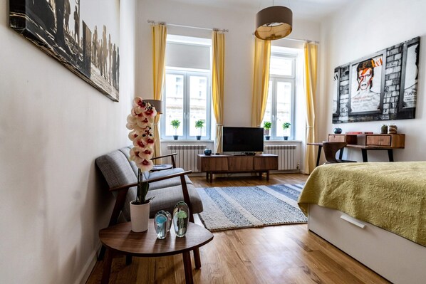 A modern bedroom with a bed, a TV, a sofa, and a dining table.