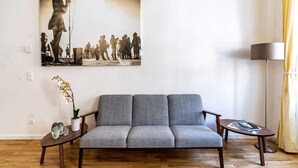 A living room with a grey sofa, a small wooden coffee table, a floor lamp, and a painting on the wall. - Boutique Prater Apartment Vienna (Vienna)