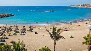 A beach with umbrellas and palm trees. - Luxury White Villa Sea View, Pool (Adeje)