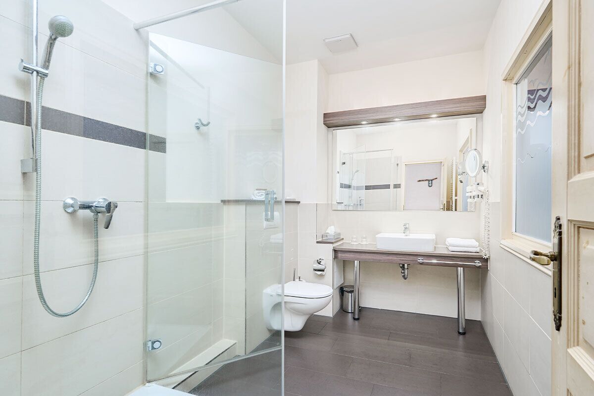 A modern bathroom with a glass-enclosed shower, a toilet, and a vanity with a mirror.
