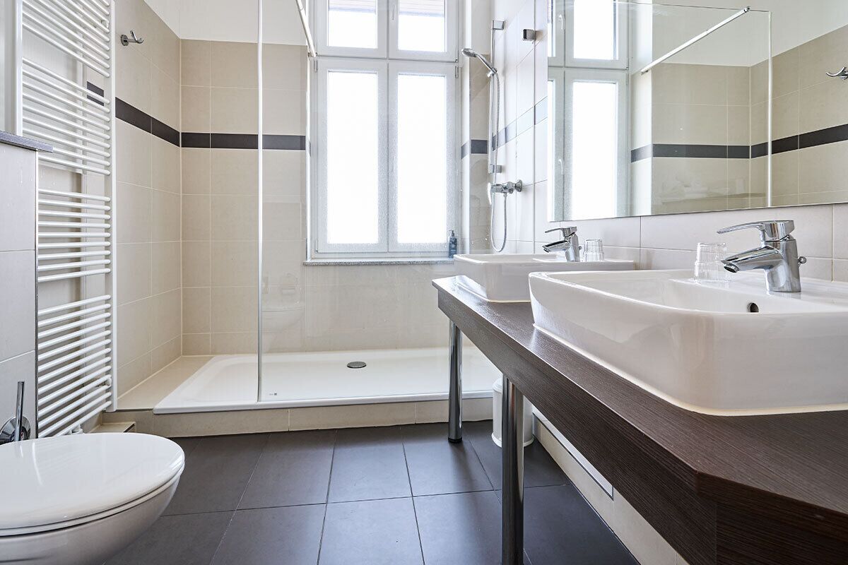 A modern bathroom with a shower, two sinks, and a toilet.