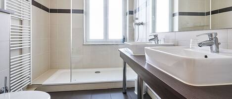A modern bathroom with a shower, two sinks, and a toilet.