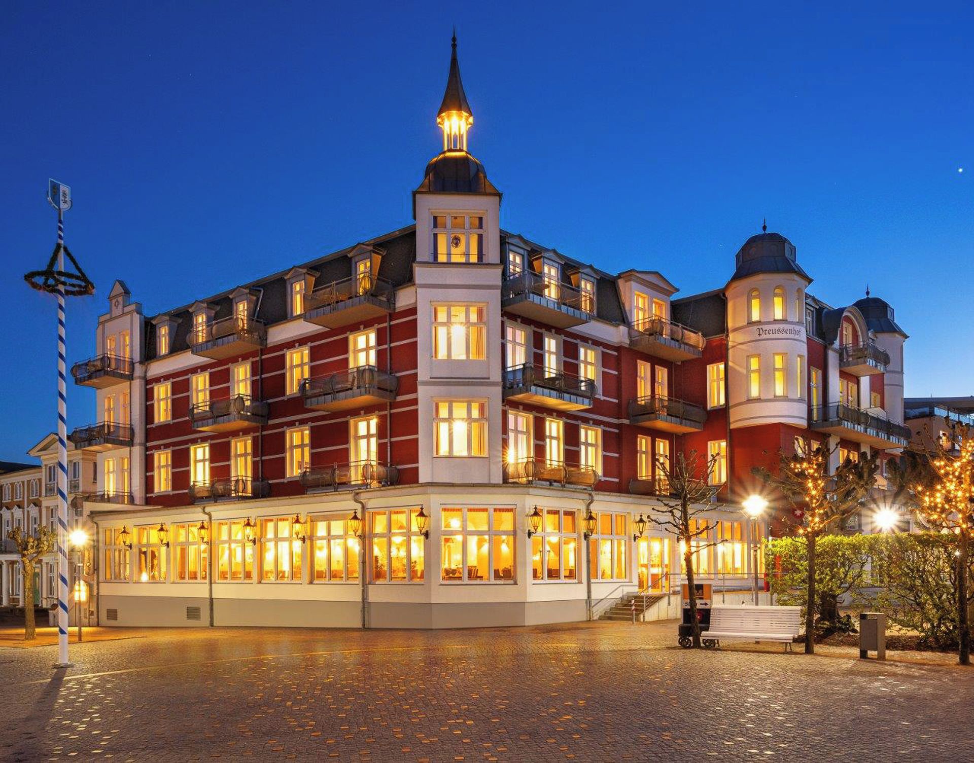 Un hotel de varios pisos con un patio central, balcones y una torre destacada.