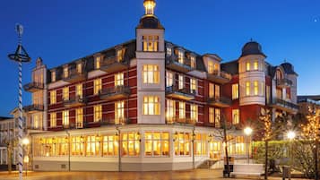 Un hotel de varios pisos con un patio central, balcones y una torre destacada.