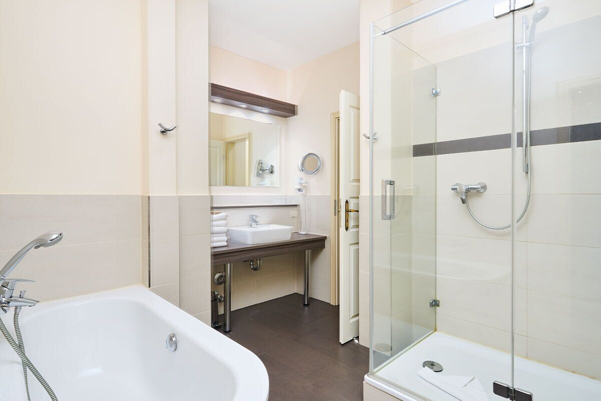 Ein modernes Badezimmer mit einer gläsernen Duschkabine, einer freistehenden Badewanne und einem Waschtisch mit Spiegel und Waschbecken.