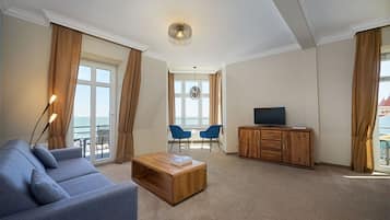 Een moderne woonkamer met een bank, een houten salontafel, een tv-kast en twee stoelen.