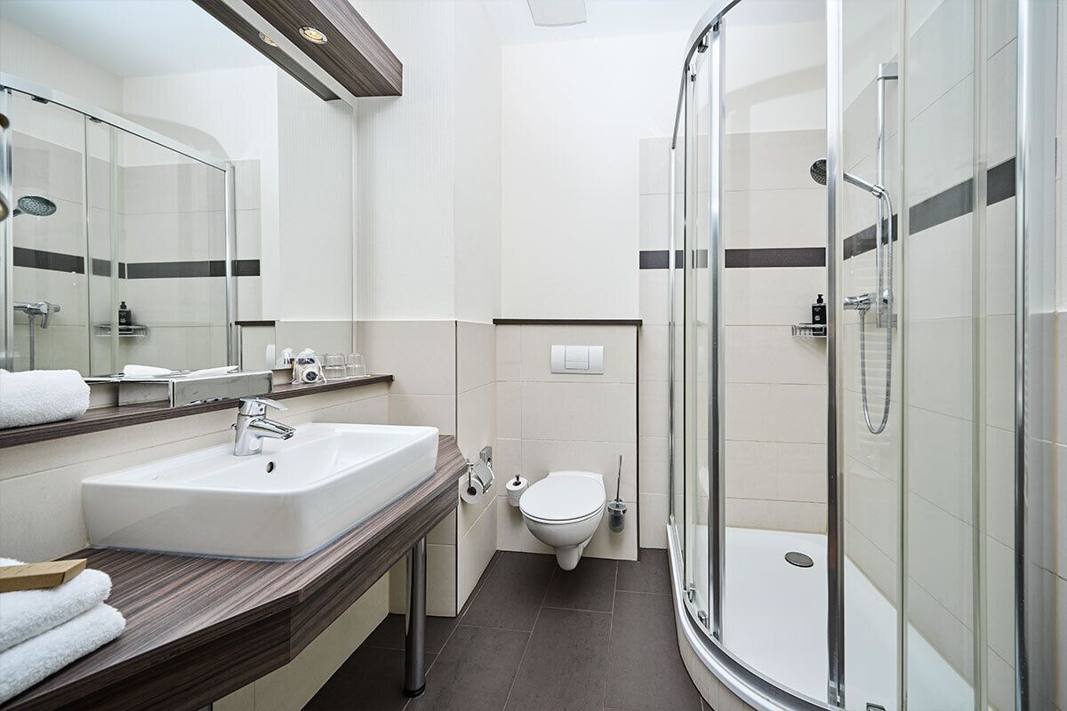 A modern bathroom with a glass-enclosed shower, a white sink, and a toilet.