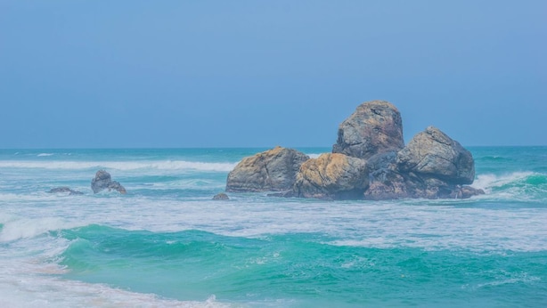 Una costa rocosa con aguas turquesas cristalinas y un cielo despejado.