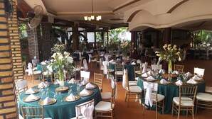A spacious outdoor dining area with round tables set with white napkins, gold chargers, and glassware. - Hotel Club Quinta Pat Resort & Restaurant (San Antonio de Oriente)