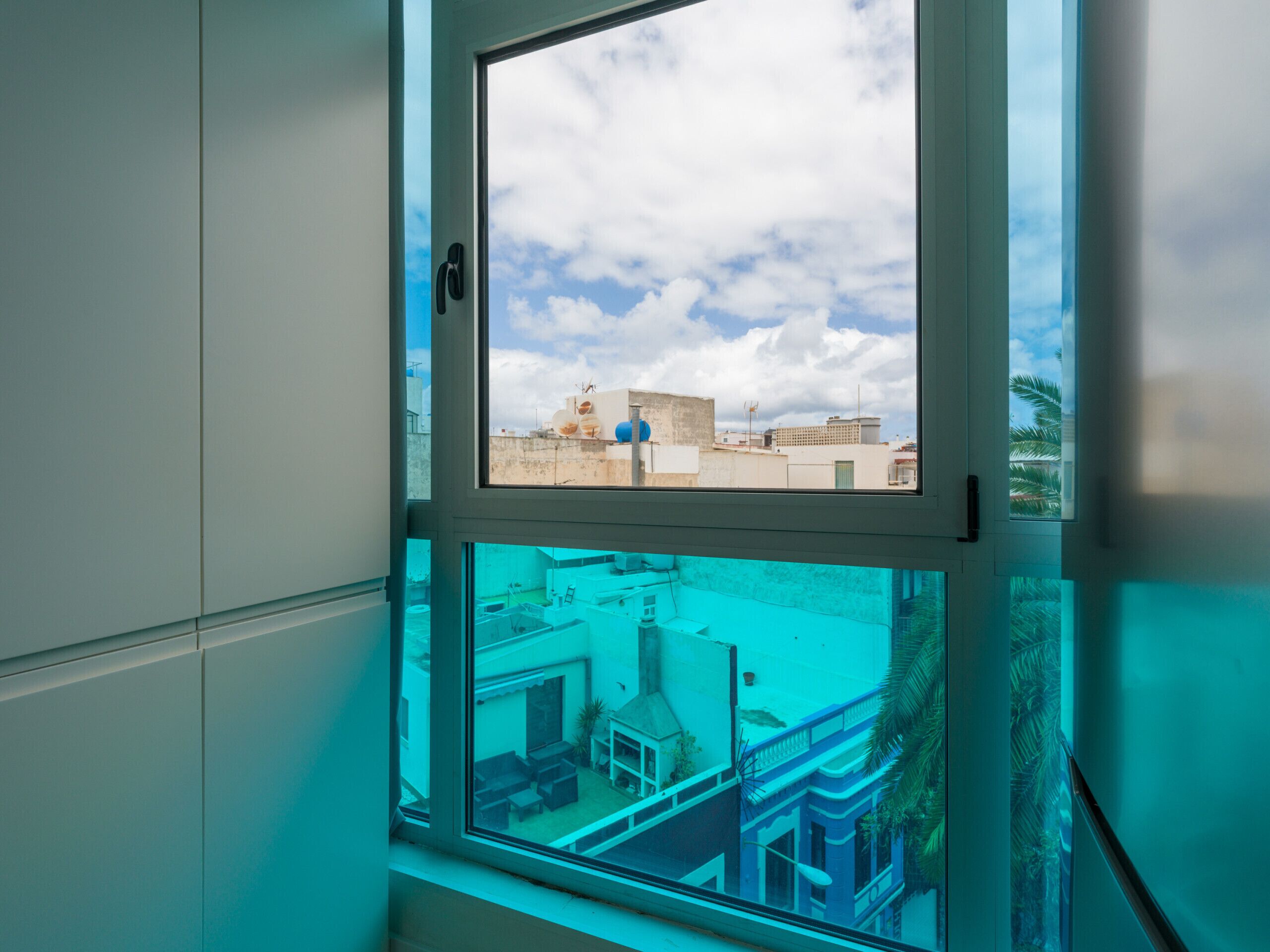 Una ventana con vistas a edificios y un cielo despejado.