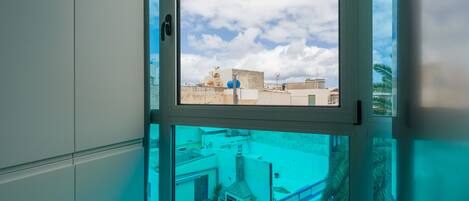 Una ventana con vistas a edificios y un cielo despejado.
