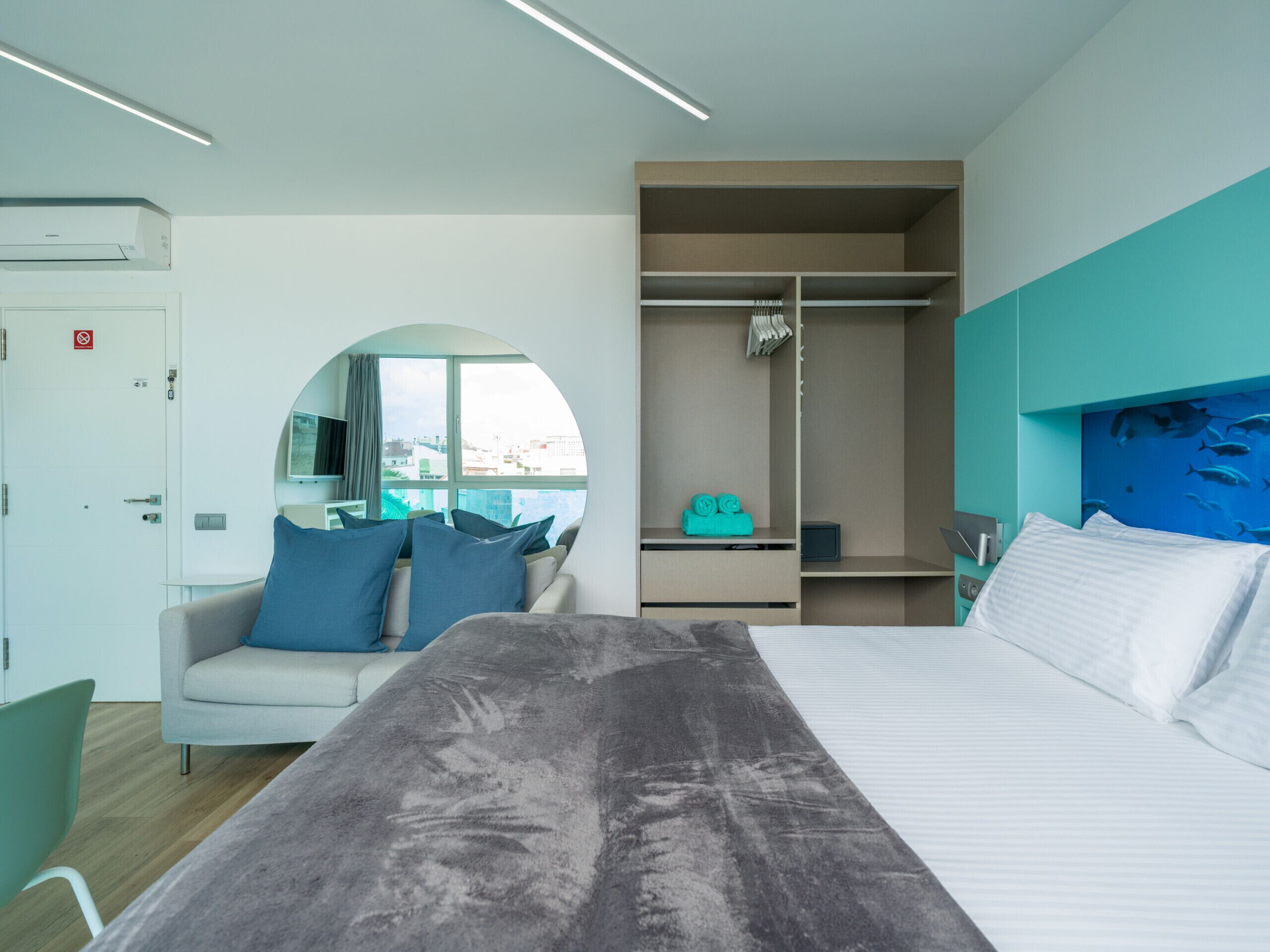 Une chambre d’hôtel moderne équipée d’un lit, d’un coin salon, d’une armoire et offrant une vue sur la ville.