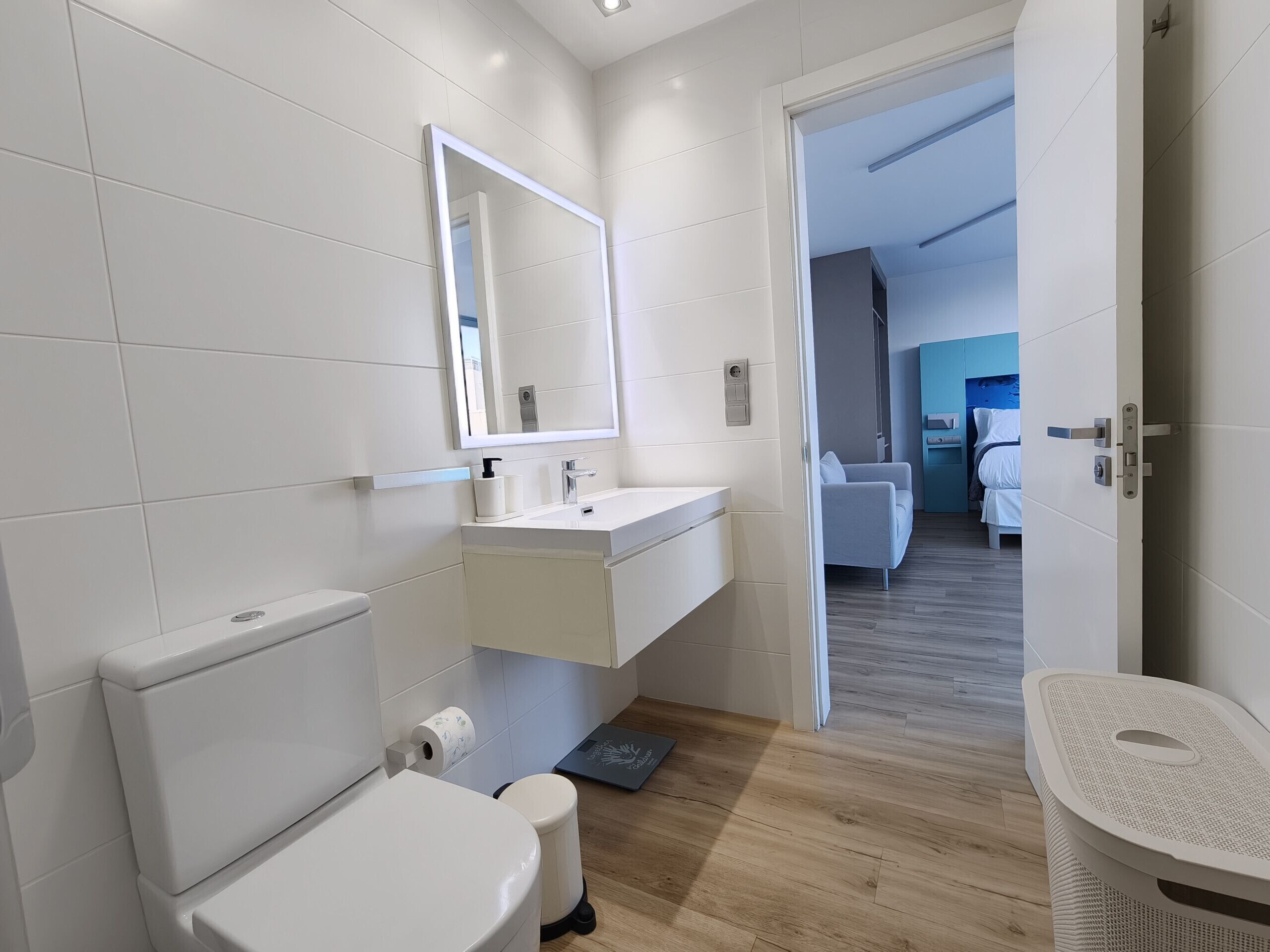 A modern bathroom with a toilet, sink, and mirror.