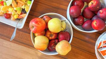 Três tigelas de fruta sobre uma mesa de madeira.