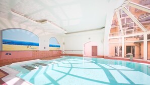 Ein überdachter Pool mit Panoramafenstern, Blick auf den Strand und einem modernen architektonischen Design.