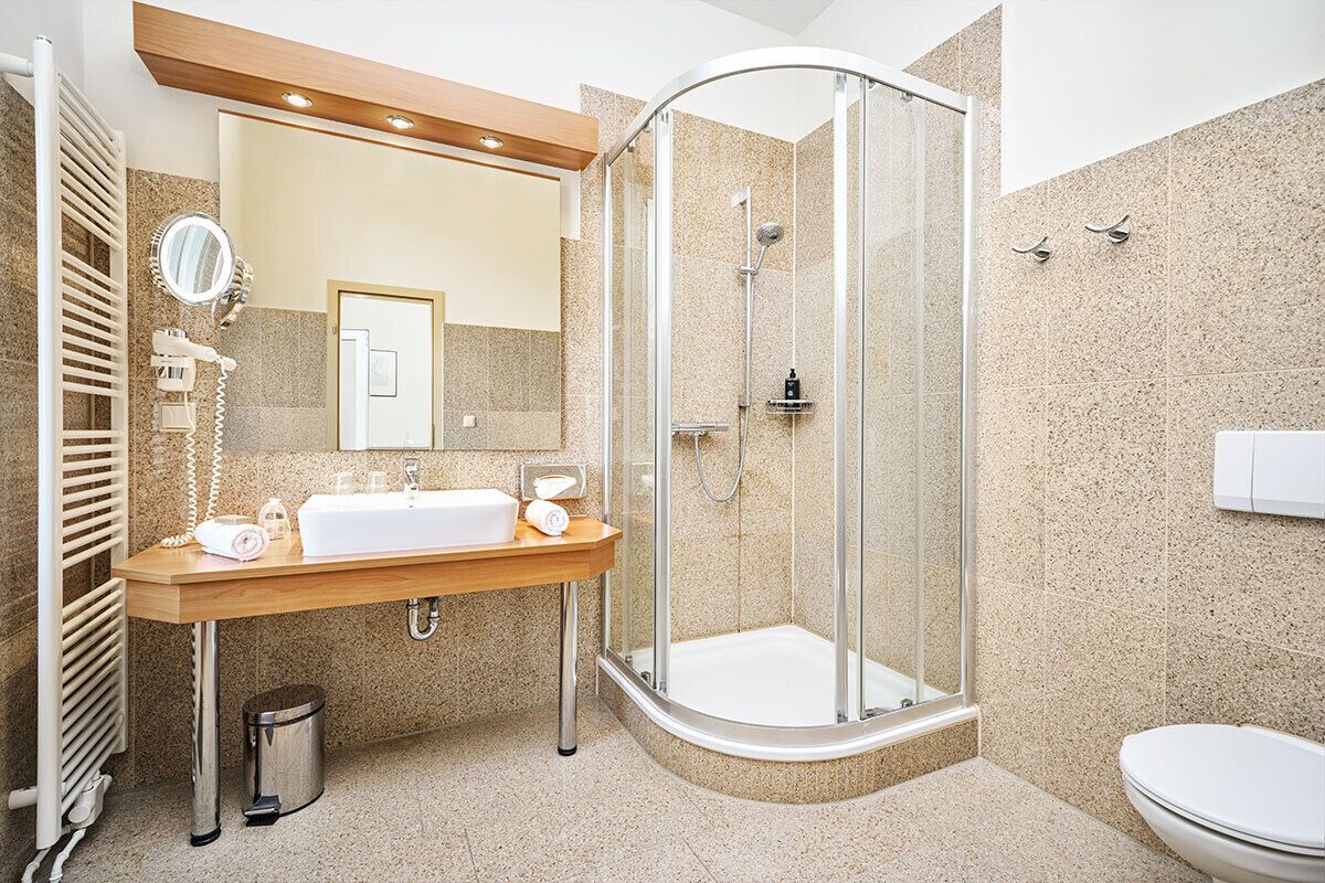 A modern bathroom with a glass-enclosed shower, a wooden vanity, and a large mirror.