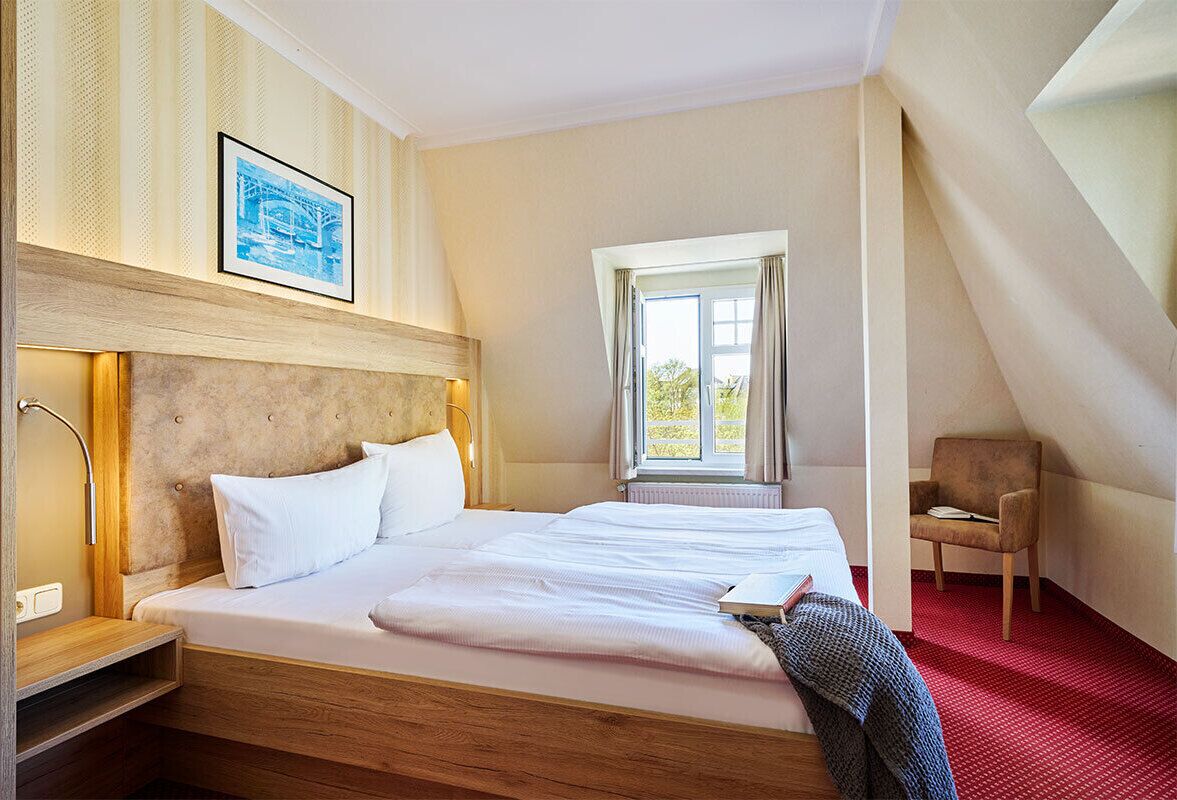 Habitación de hotel con una cama grande, una silla, una ventana con cortinas e imagen enmarcada en la pared.