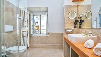 Un bagno moderno con box doccia in vetro, un water, un lavandino con specchio e una finestra che offre vista all'esterno.