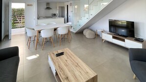 Ein moderner Wohnraum mit Essbereich, einer Küche, einer Treppe und einem Fernseher.