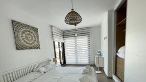 Ein Hotelzimmer mit einem großen Bett, einem Nachttisch, einer Lampe, einem Kleiderschrank und Blick aus dem Fenster.