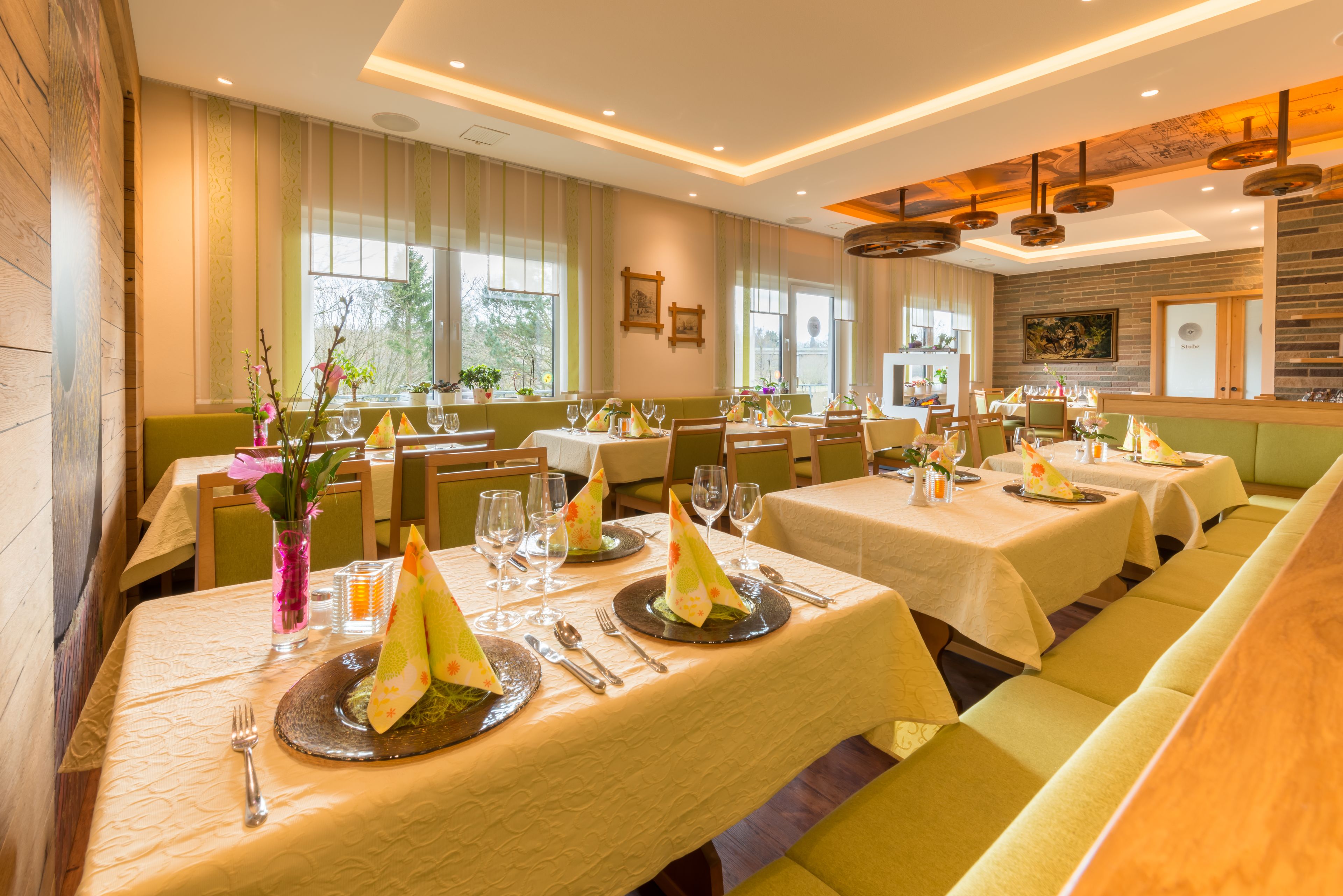 Un restaurant doté de nombreuses tables dressées pour le service, avec une disposition soignée de la vaisselle et des chaises.