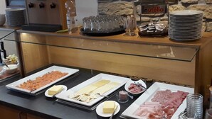 Een buffet met diverse gerechten, waaronder vleeswaren, kazen en gebak.