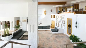 A spacious indoor area with a stone floor, a wooden ceiling, and a seating area with a sofa and chairs. There are plants and a wall with framed pictures. - 1107 Sea view super Playa Las Americas (Playa de las Américas)