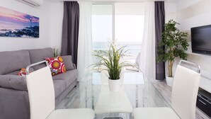 A modern living room with a grey sofa, a glass coffee table, and a TV mounted on the wall. - 1107 Sea view super Playa Las Americas (Playa de las Américas)